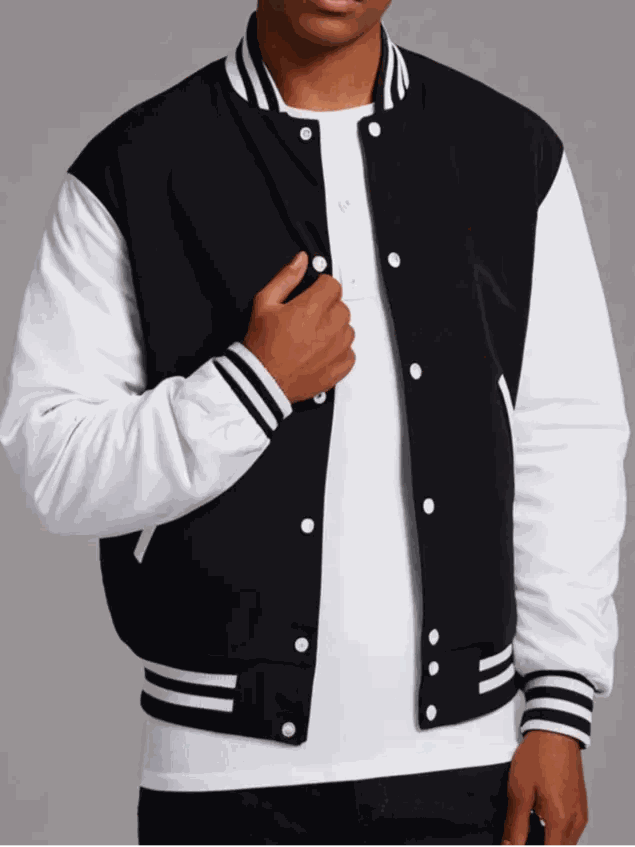 Person wearing a black and white varsity jacket on a gray background