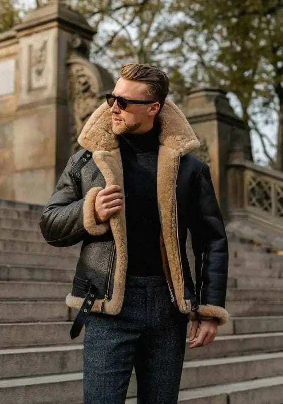 Man wearing a stylish black shearling leather jacket outdoors on stone steps in autumn setting