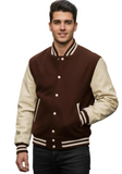 A man wearing a brown and cream varsity jacket standing on a blurred city street.