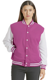 A woman modeling a magenta and white varsity jacket with white sleeves, white buttons, and white striped ribbed trim, paired with dark gray jeans against a light gray studio background.