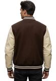 A man viewed from behind wearing a brown and cream varsity jacket with striped ribbing, set against a blurred outdoor street background.